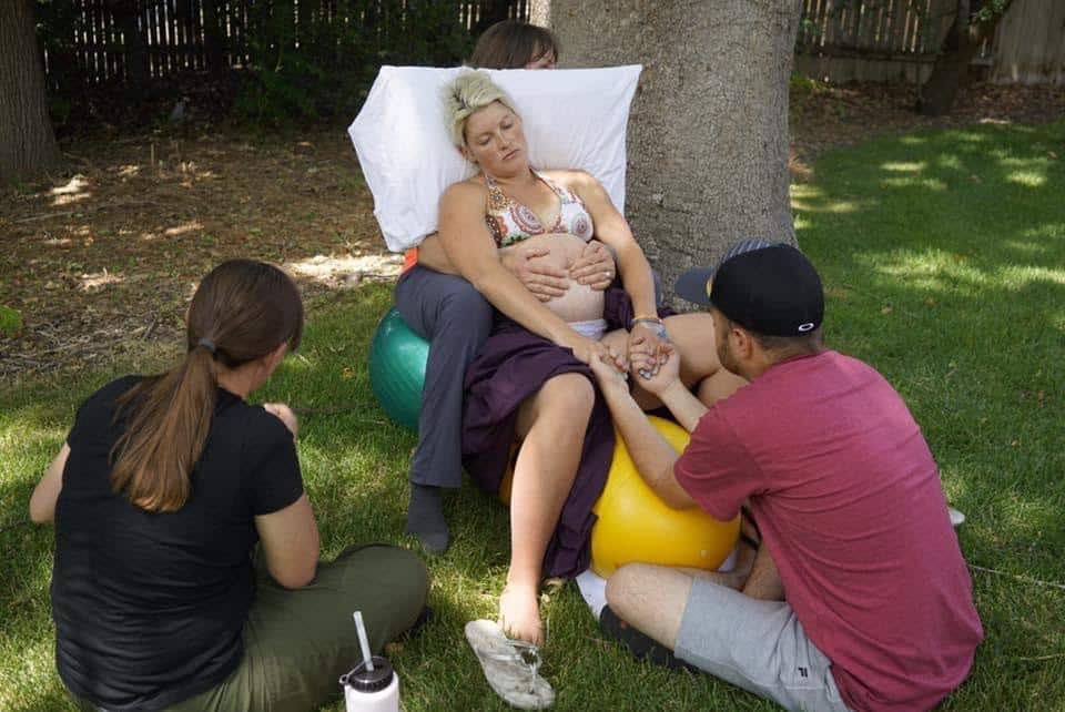 woman in backyard with husband and doula during home labor