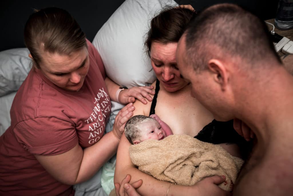 woman holding baby after birth with husband and doula